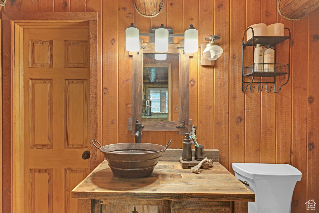 Bathroom featuring wooden walls, vanity, and toilet