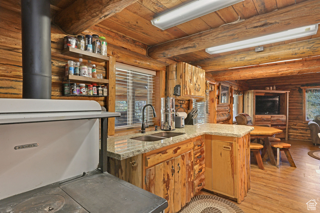 Kitchen featuring light wood-type flooring, kitchen peninsula, a healthy amount of sunlight, and sink