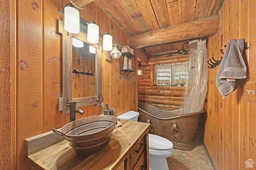 Bathroom with wood ceiling, wooden walls, toilet, and vanity