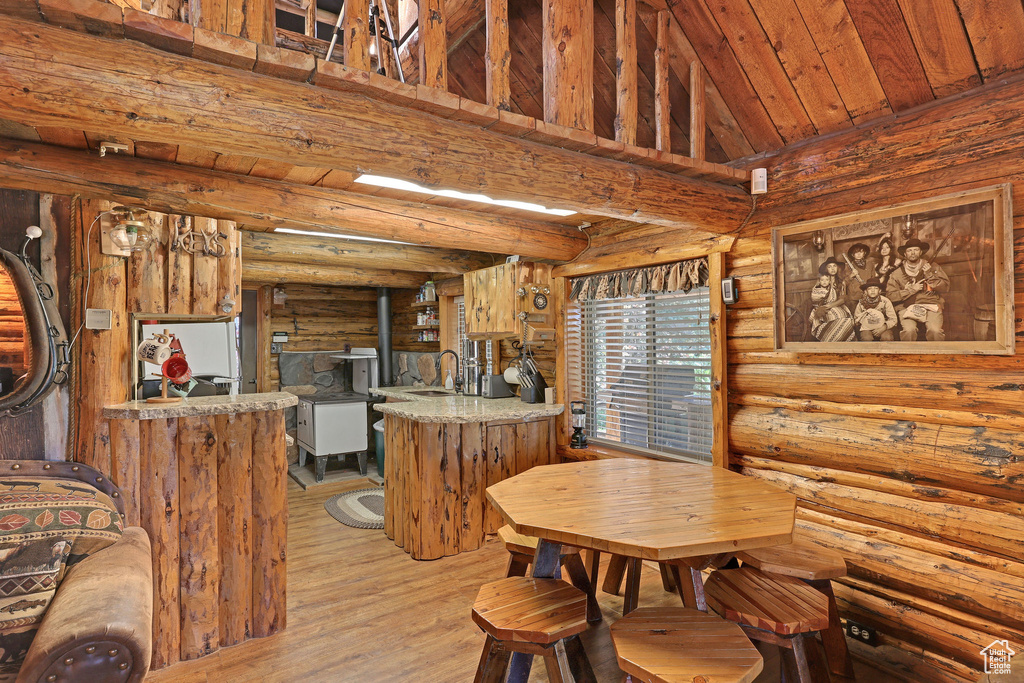 Dining space featuring wood ceiling, log walls, sink, and light hardwood / wood-style flooring