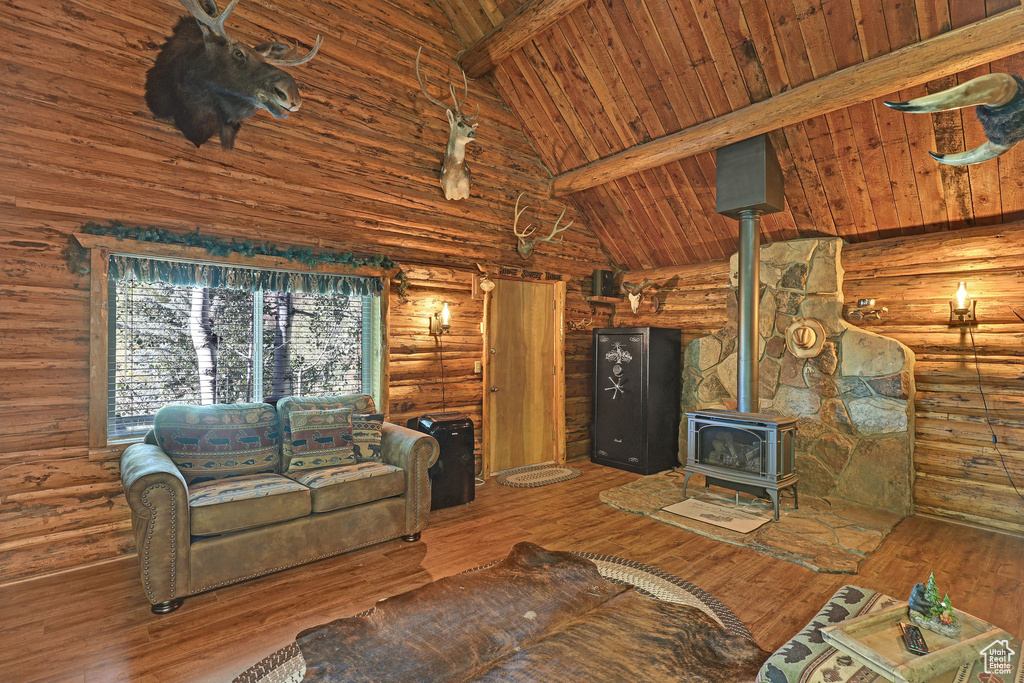 Living room with wood ceiling, high vaulted ceiling, a wood stove, beam ceiling, and hardwood / wood-style flooring