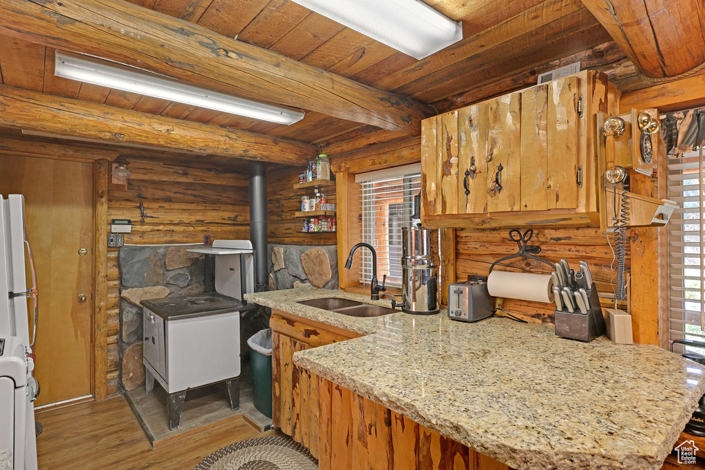 Kitchen with beamed ceiling, sink, kitchen peninsula, hardwood / wood-style flooring, and wooden ceiling