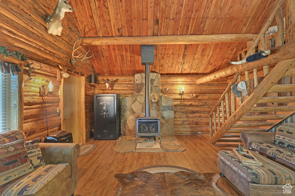 Unfurnished living room featuring wood ceiling, lofted ceiling with beams, a wood stove, hardwood / wood-style flooring, and rustic walls