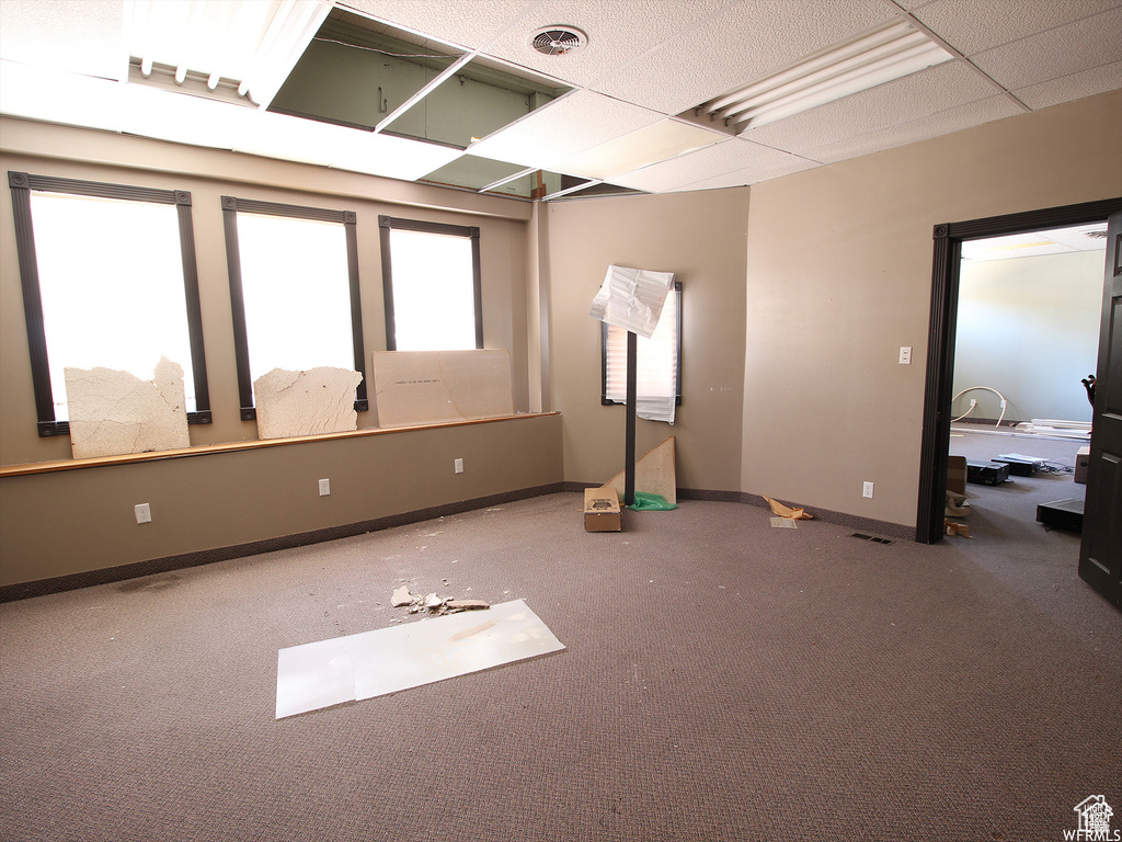 Unfurnished room featuring carpet and a drop ceiling