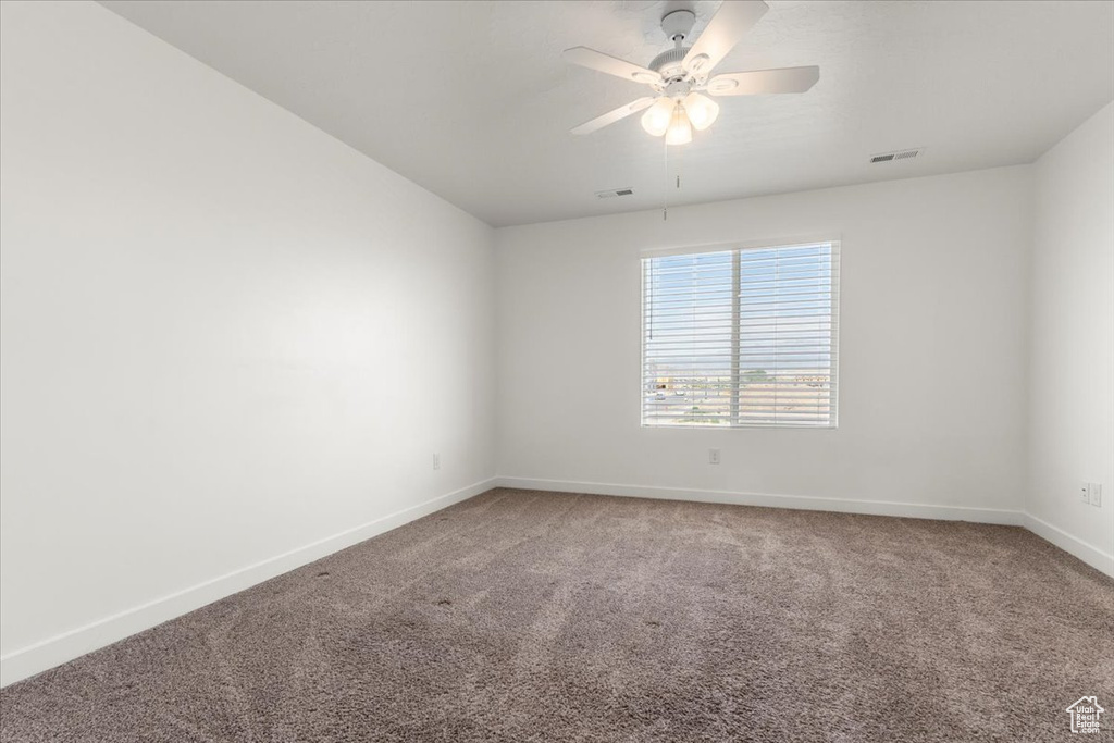 Carpeted spare room featuring ceiling fan