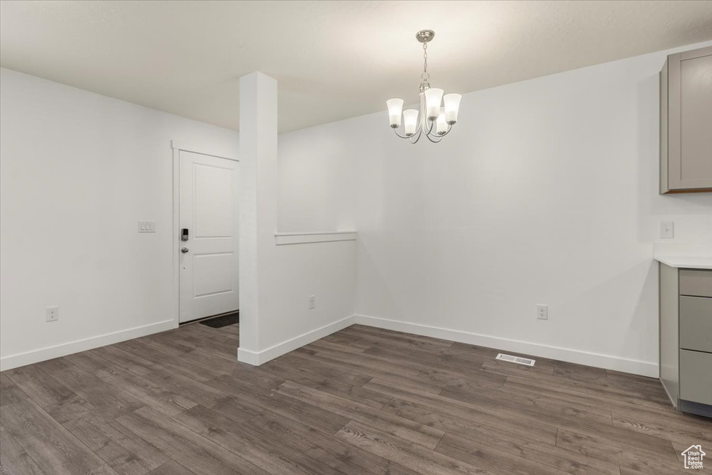 Unfurnished dining area featuring dark hardwood / wood-style floors and a chandelier