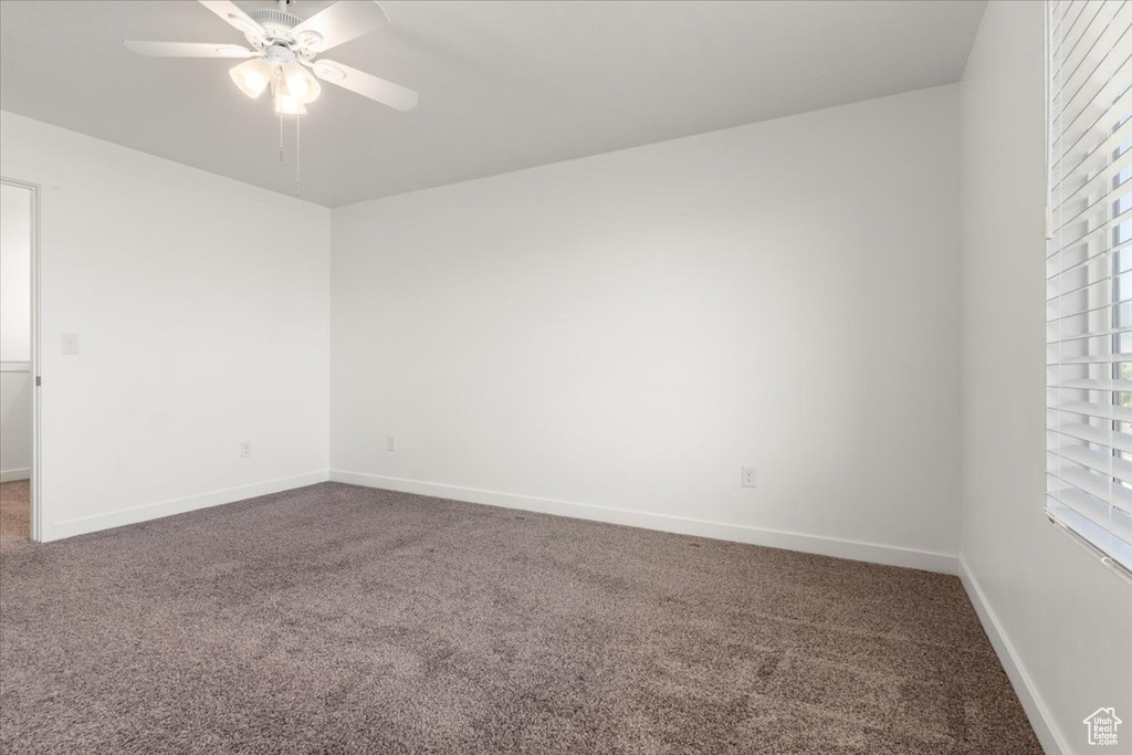 Carpeted empty room with a healthy amount of sunlight and ceiling fan