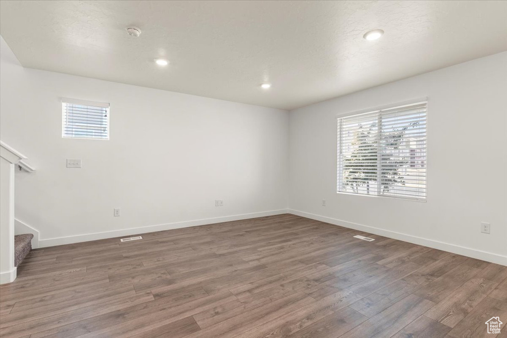 Empty room with a healthy amount of sunlight and dark hardwood / wood-style flooring