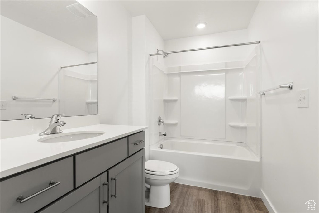 Full bathroom with wood-type flooring, vanity, toilet, and shower / washtub combination