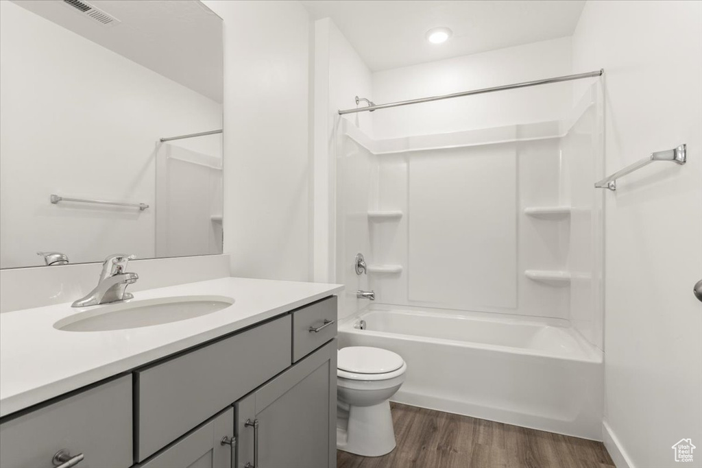 Full bathroom featuring vanity, hardwood / wood-style floors, toilet, and washtub / shower combination