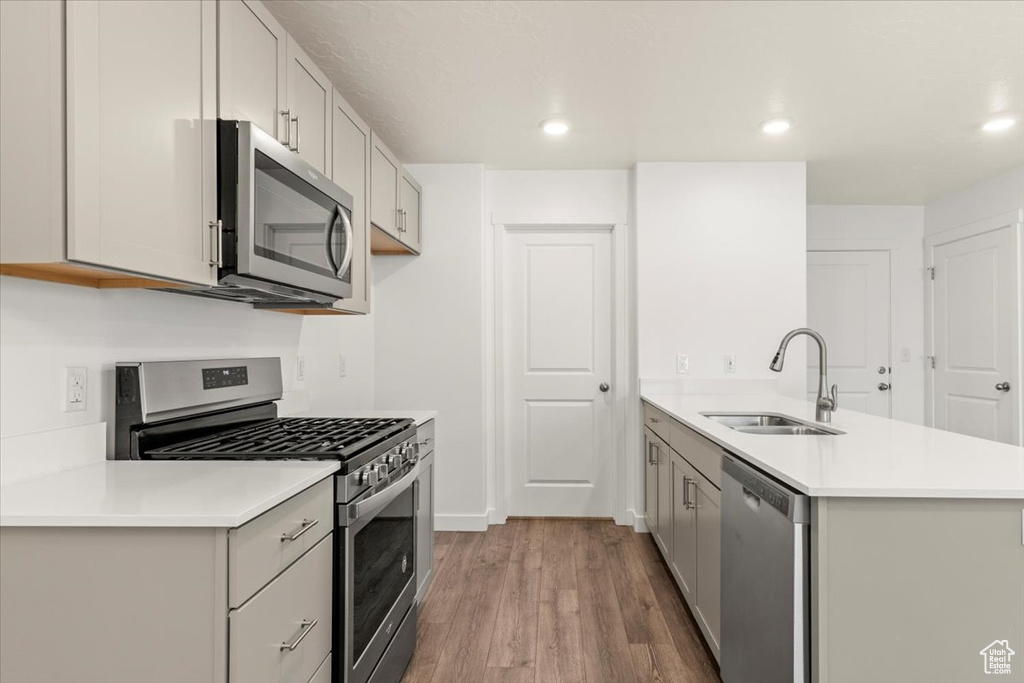 Kitchen featuring appliances with stainless steel finishes, wood-type flooring, sink, and gray cabinets