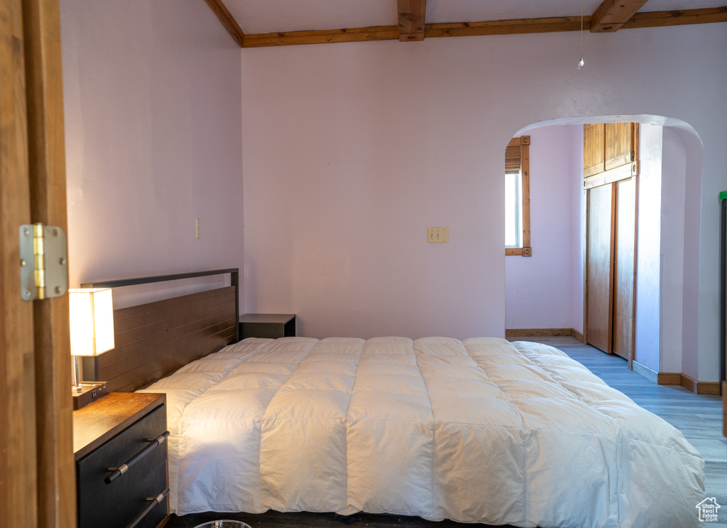 Bedroom featuring light hardwood / wood-style floors, beamed ceiling, and ceiling fan