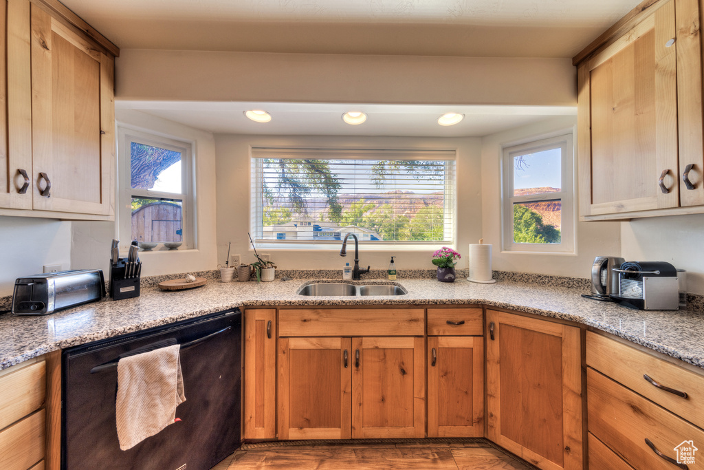 Kitchen featuring light stone counters, dishwasher, and sink
