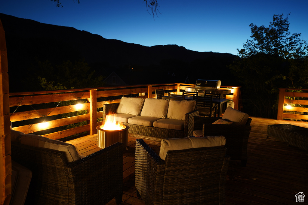 Patio terrace at dusk with an outdoor hangout area and a deck with mountain view