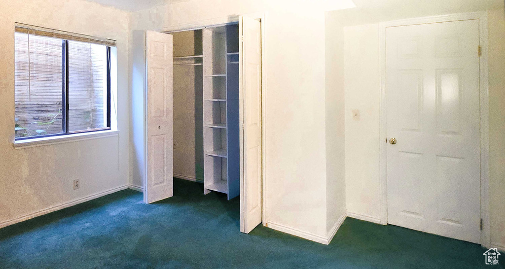 Unfurnished bedroom featuring dark colored carpet and a closet