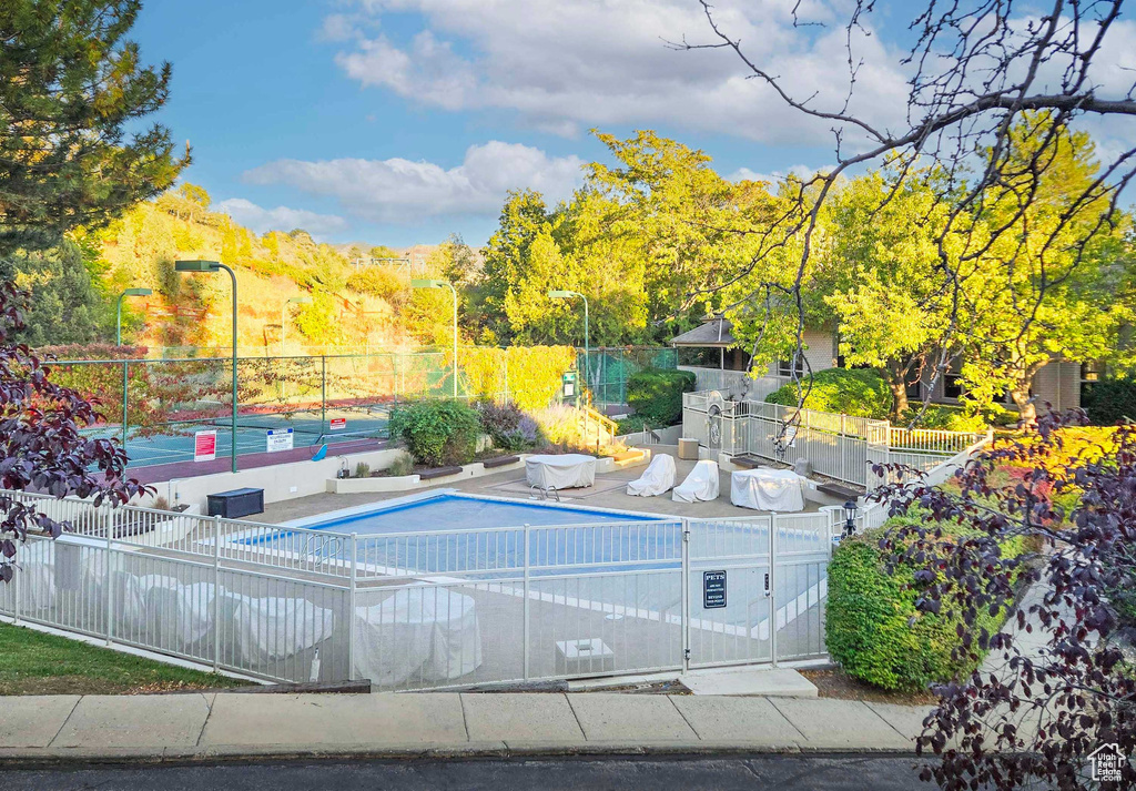 View of swimming pool featuring tennis court