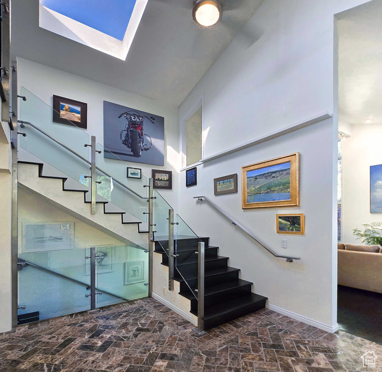 Stairs with lofted ceiling with skylight