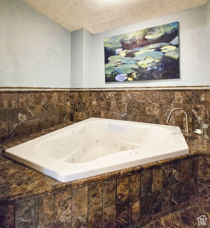 Bathroom featuring tiled bath and a textured ceiling