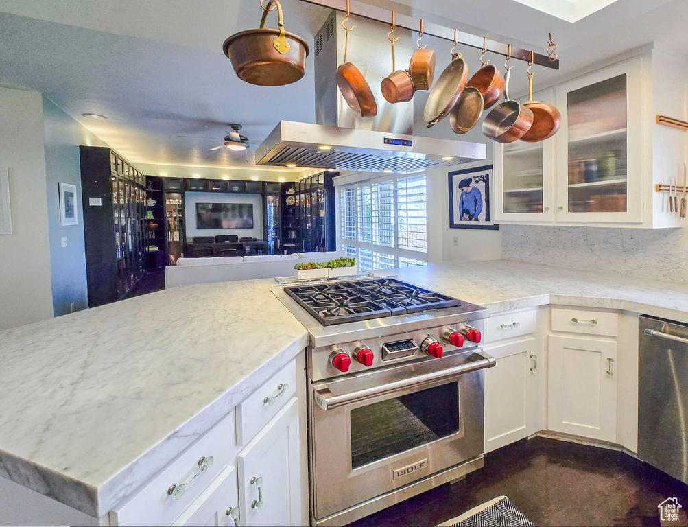 Kitchen featuring kitchen peninsula, stainless steel appliances, white cabinetry, and island range hood