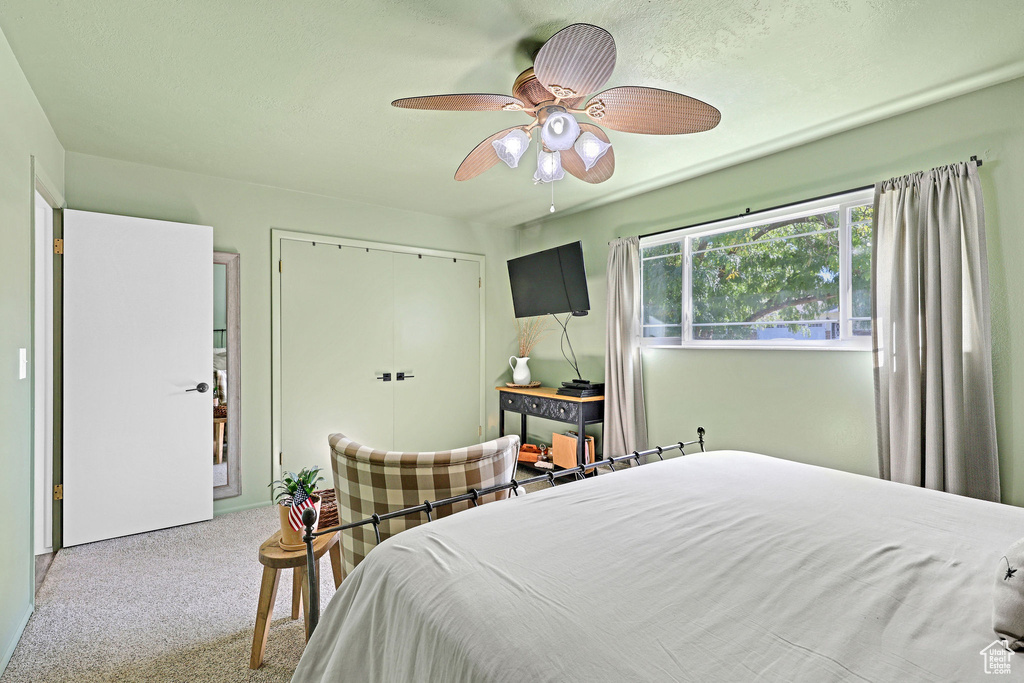 Carpeted bedroom with ceiling fan and a closet