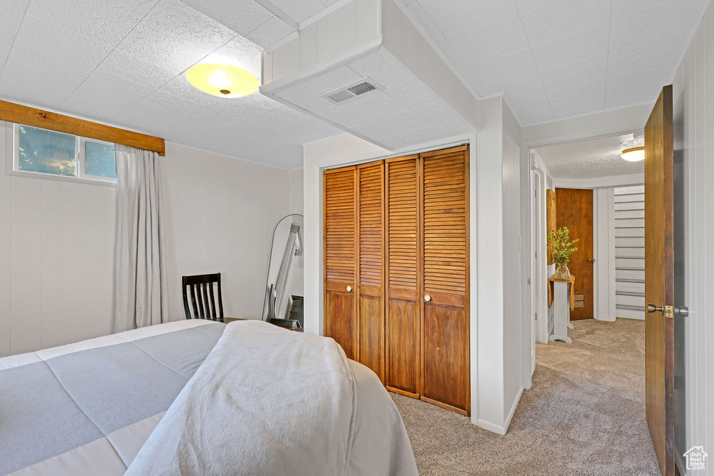 Carpeted bedroom featuring wooden walls and a closet