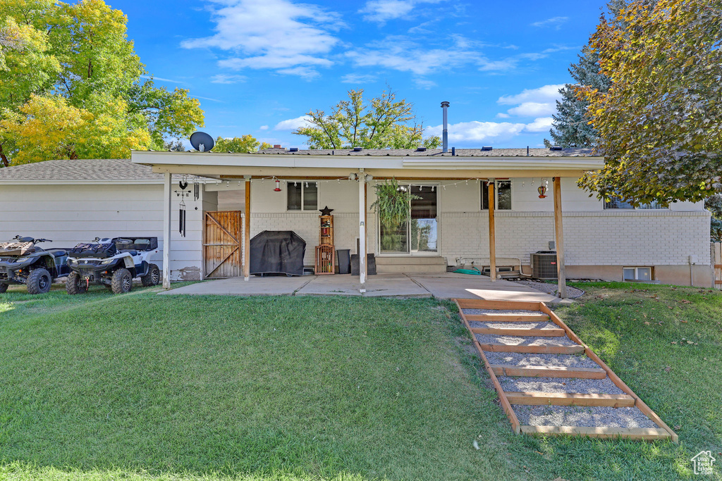 Back of property featuring a lawn, a patio, and central AC