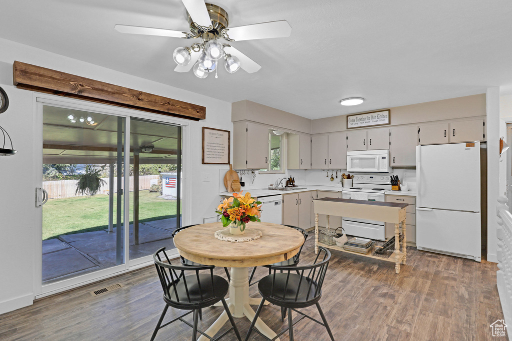 Dining area with ceiling fan, dark wood-type flooring, and sink