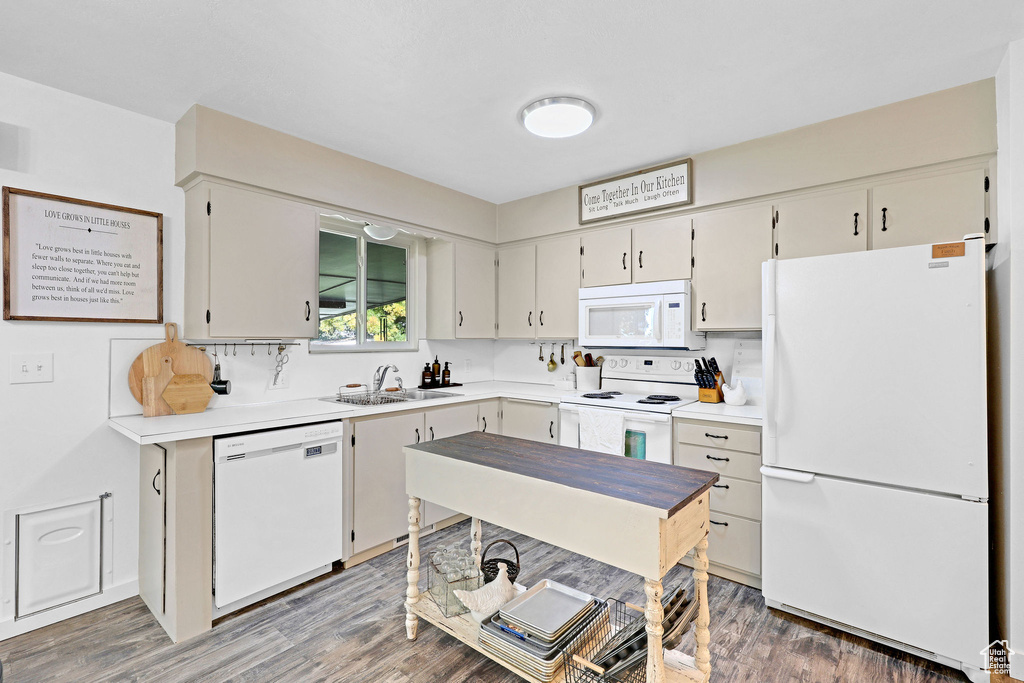 Kitchen featuring white appliances, white cabinetry, dark hardwood / wood-style floors, and sink