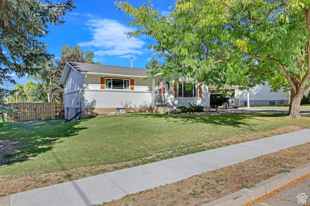 View of front of home with a carport and a front lawn