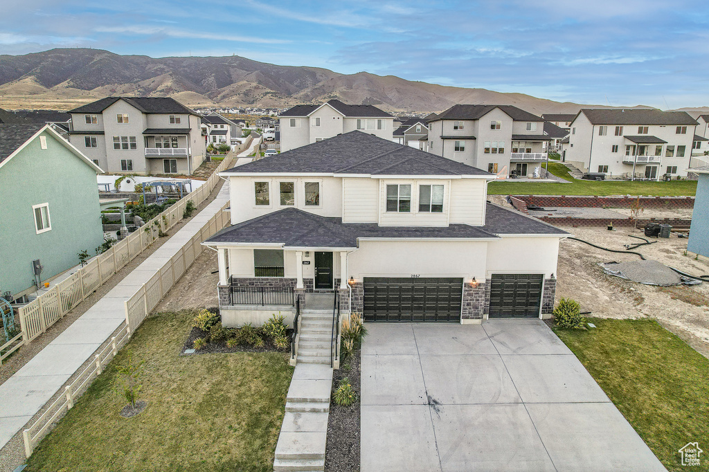 View of front of home featuring a front yard, a mountain view, a garage, and covered porch