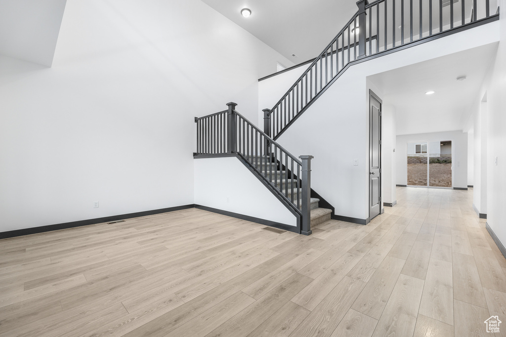 Staircase featuring a towering ceiling and hardwood / wood-style floors