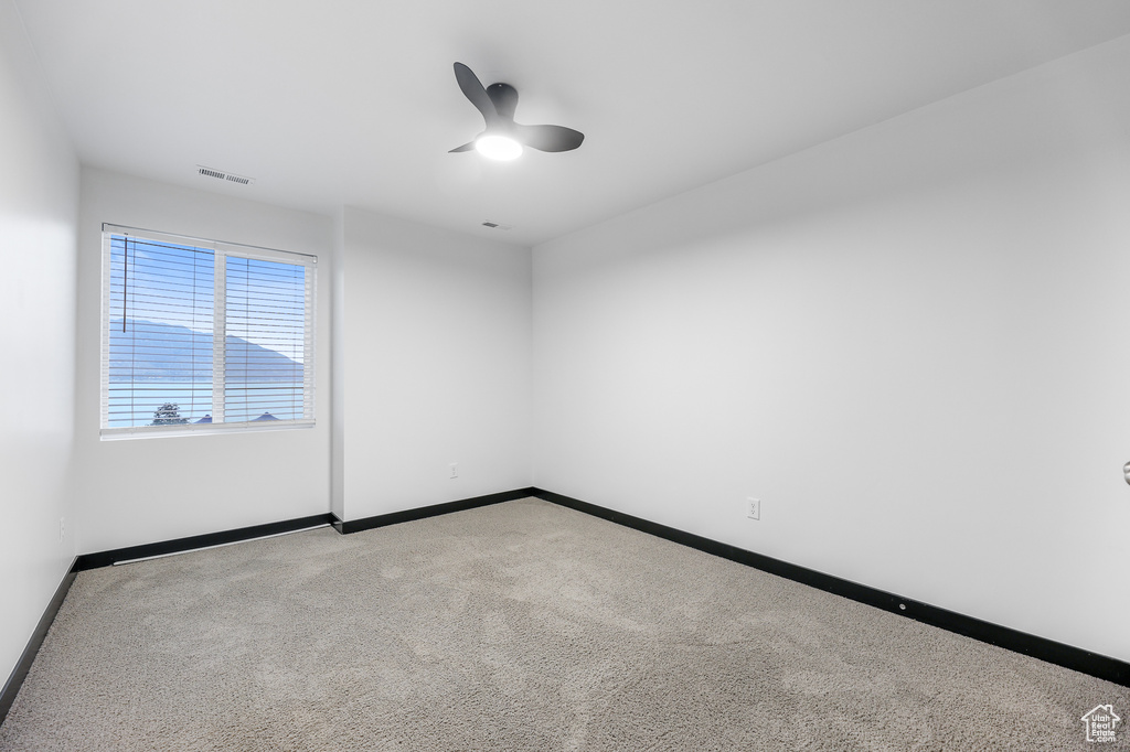 Carpeted empty room featuring ceiling fan