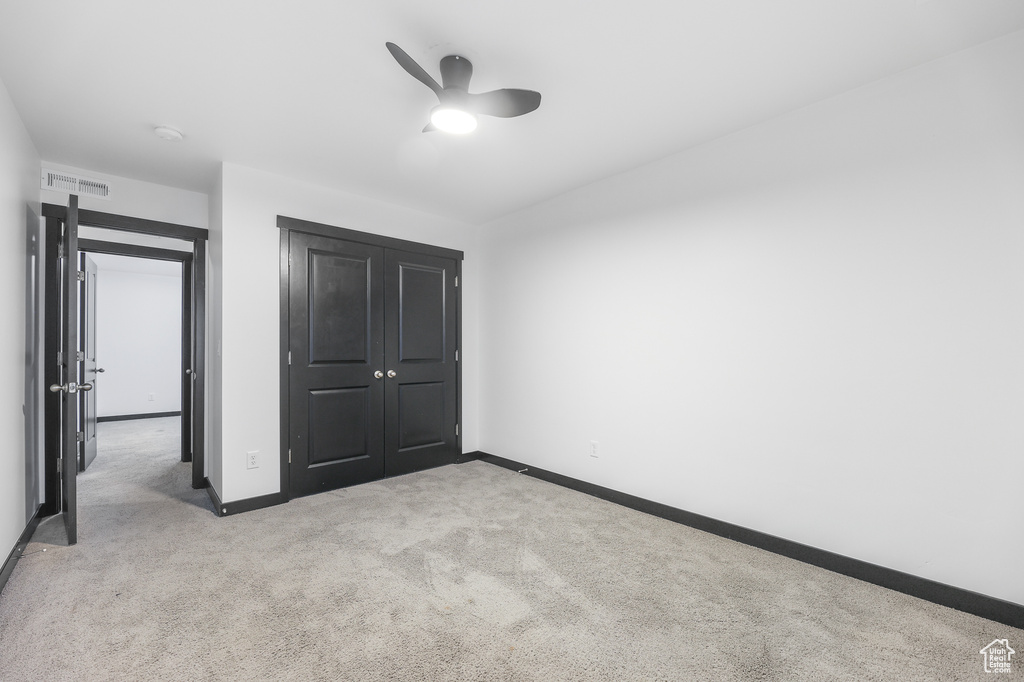 Unfurnished bedroom featuring a closet, ceiling fan, and light colored carpet