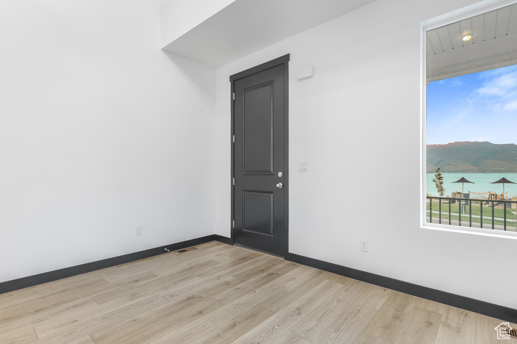 Empty room featuring light hardwood / wood-style floors and a water view