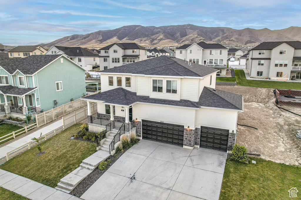 View of front facade with a mountain view, a garage, and a front lawn