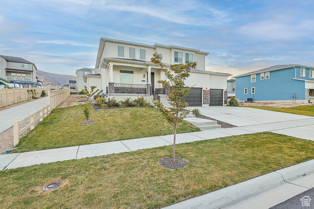 View of front of house featuring a front yard, a garage, and covered porch