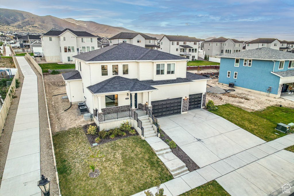 View of front facade featuring a mountain view, covered porch, a front yard, and a garage