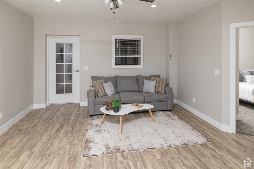 Living room with a textured ceiling, ceiling fan, and hardwood / wood-style flooring