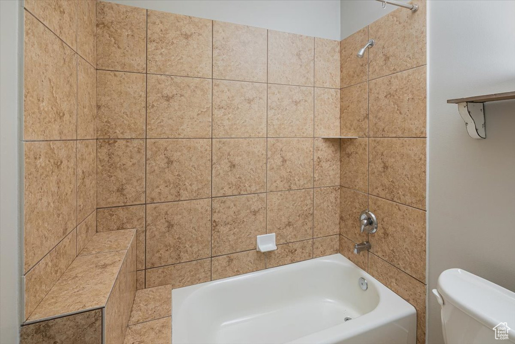 Bathroom featuring tiled shower / bath combo and toilet