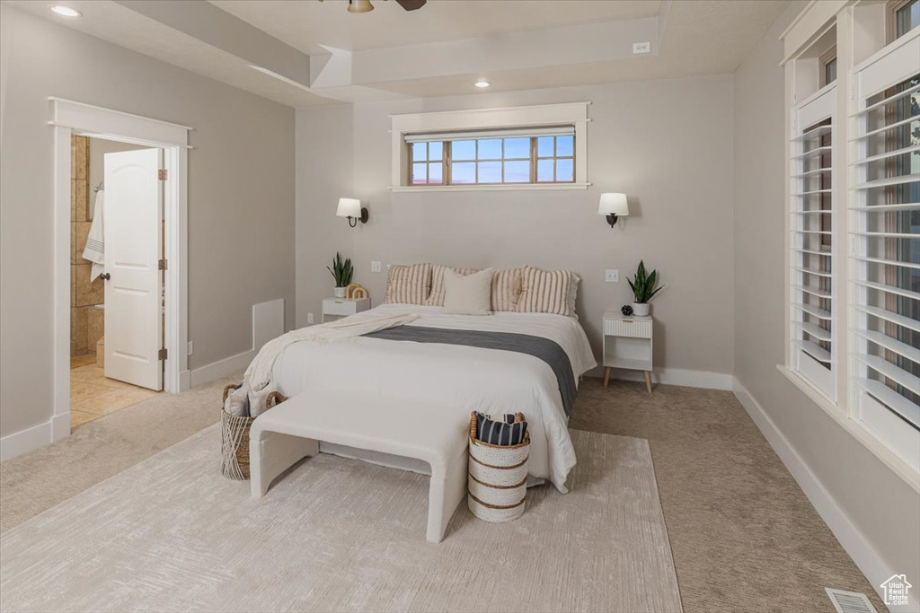 Carpeted bedroom featuring ceiling fan and ensuite bath