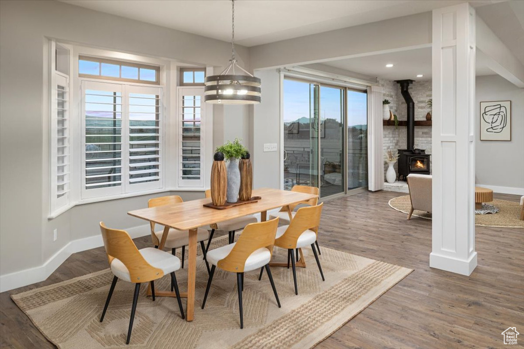 Dining space with a chandelier, hardwood / wood-style floors, and a wood stove