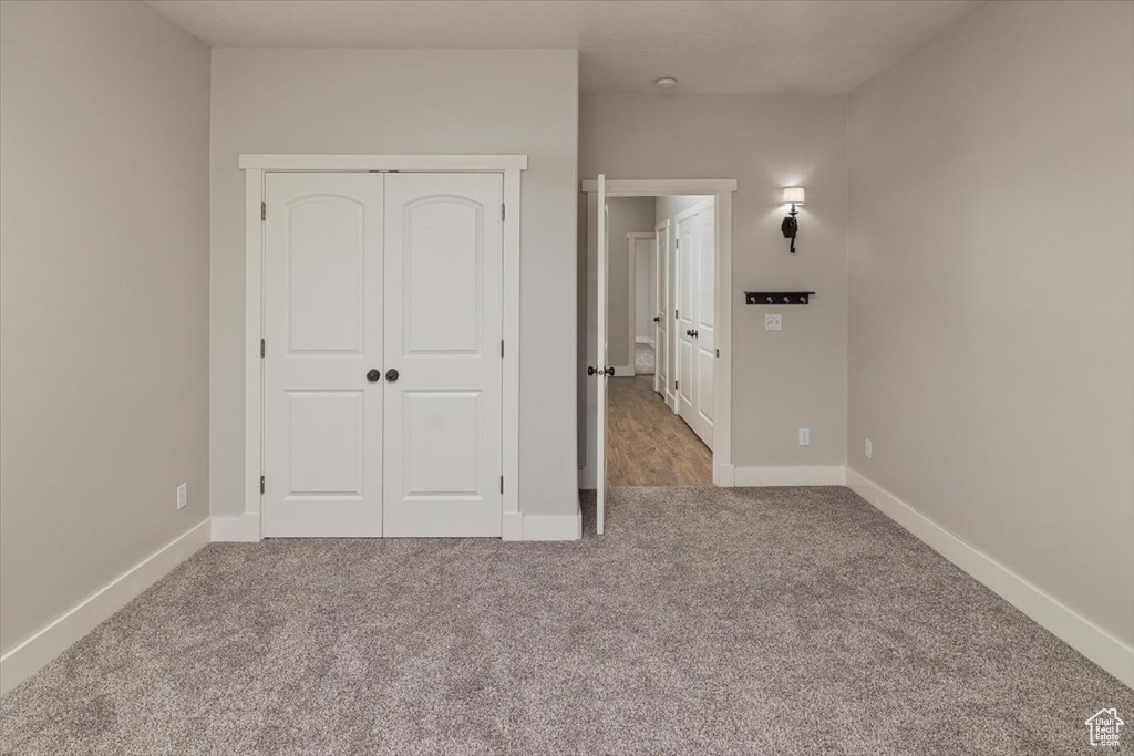 Unfurnished bedroom featuring a closet and light colored carpet