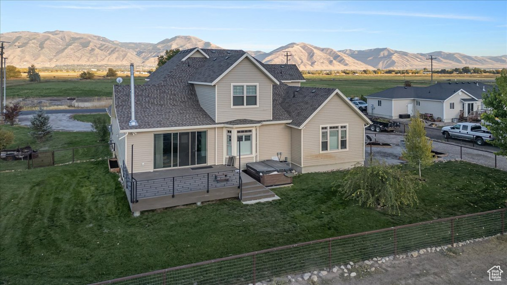 Back of house with a lawn and a deck with mountain view