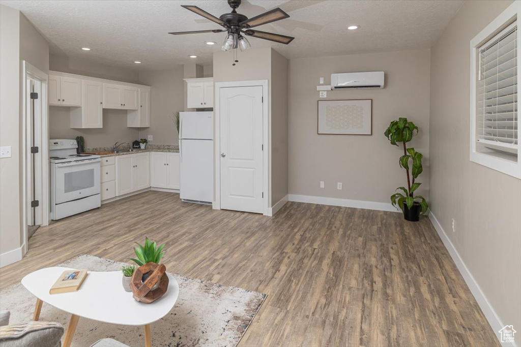 Kitchen with wood-type flooring, white appliances, and white cabinetry