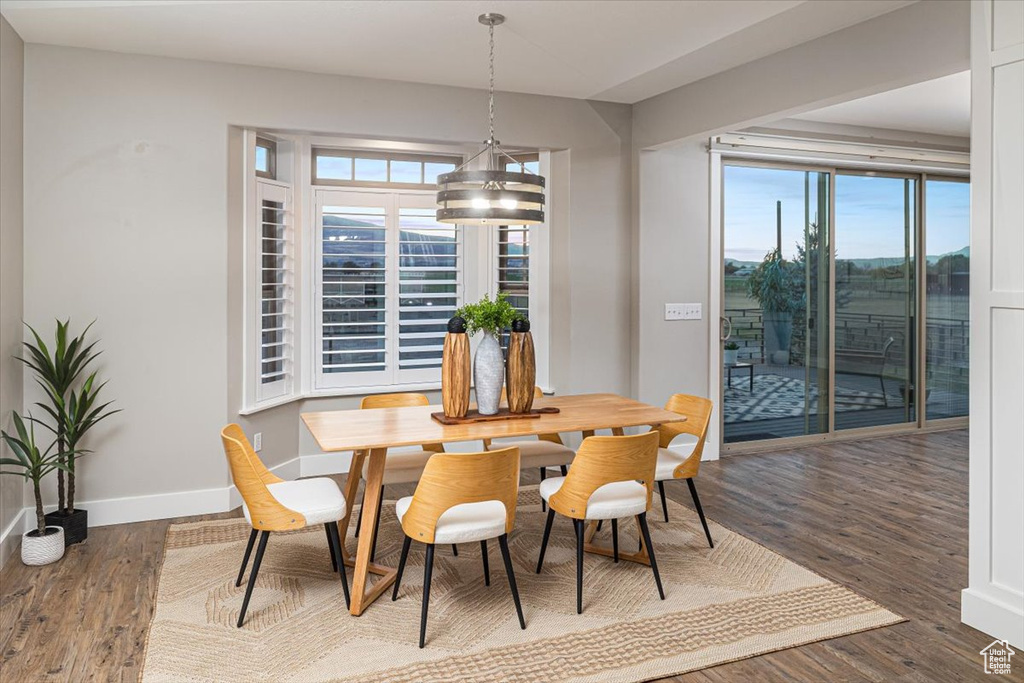 Dining area with a healthy amount of sunlight, dark wood-type flooring, and a notable chandelier