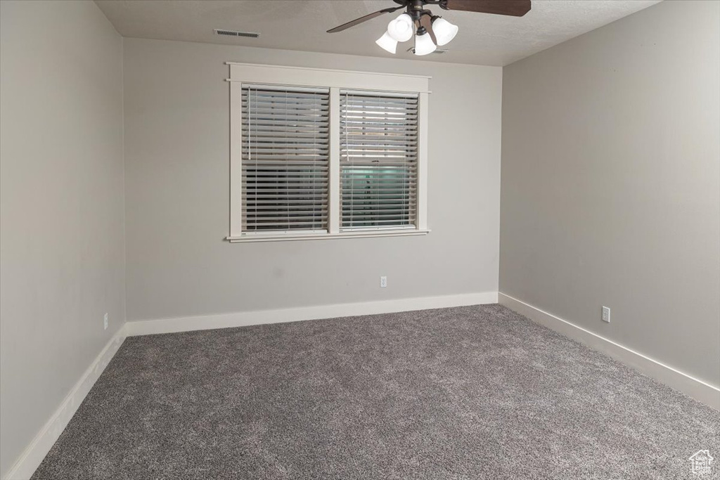 Empty room featuring ceiling fan and carpet floors