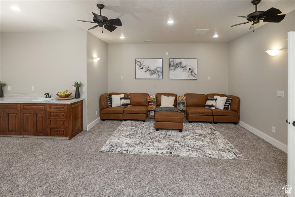 Living room featuring light carpet, ceiling fan, and sink