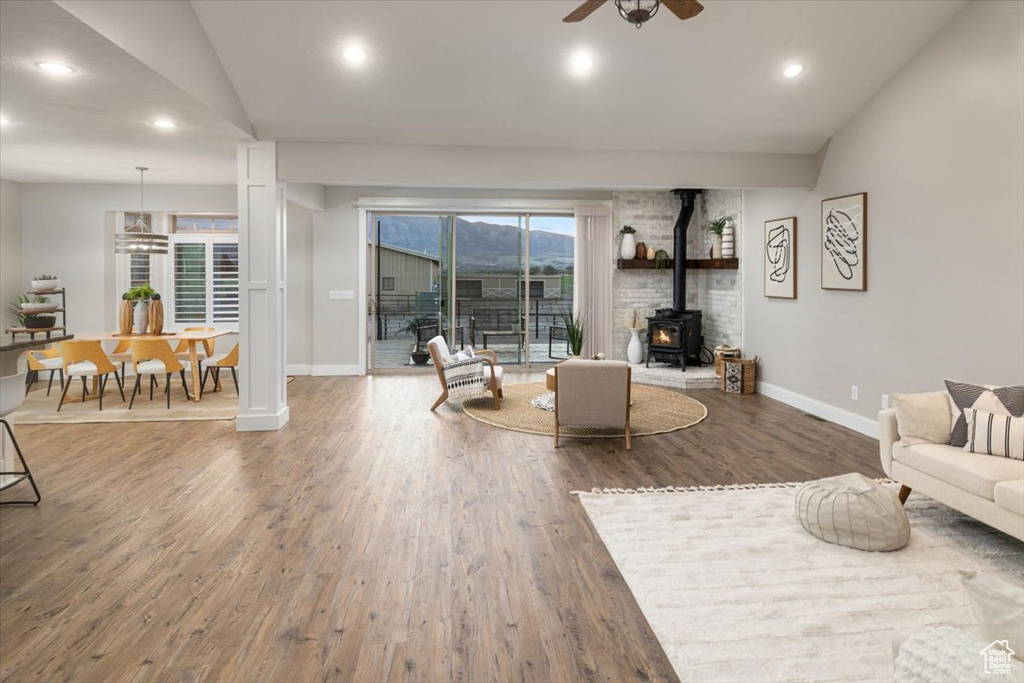 Living room featuring lofted ceiling, ceiling fan, a wood stove, and hardwood / wood-style flooring