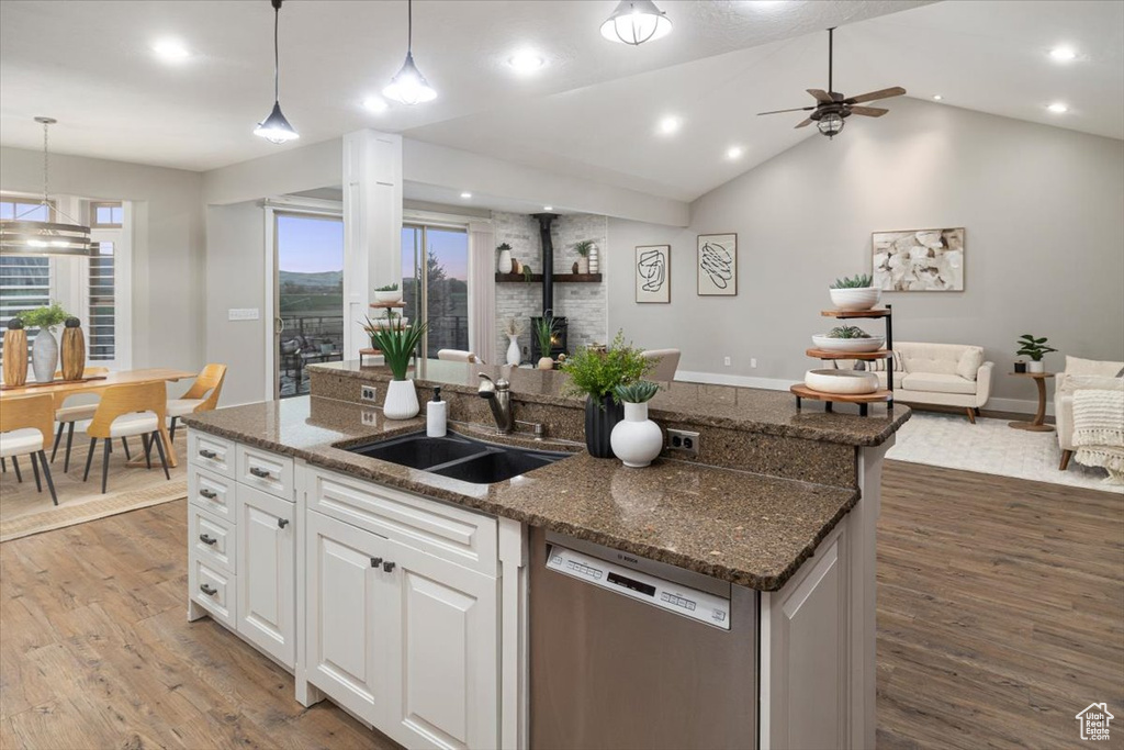 Kitchen featuring white cabinets, dishwasher, pendant lighting, a wood stove, and sink