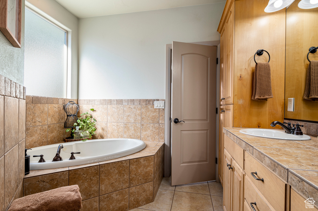 Bathroom with tiled tub, vanity, and tile patterned floors